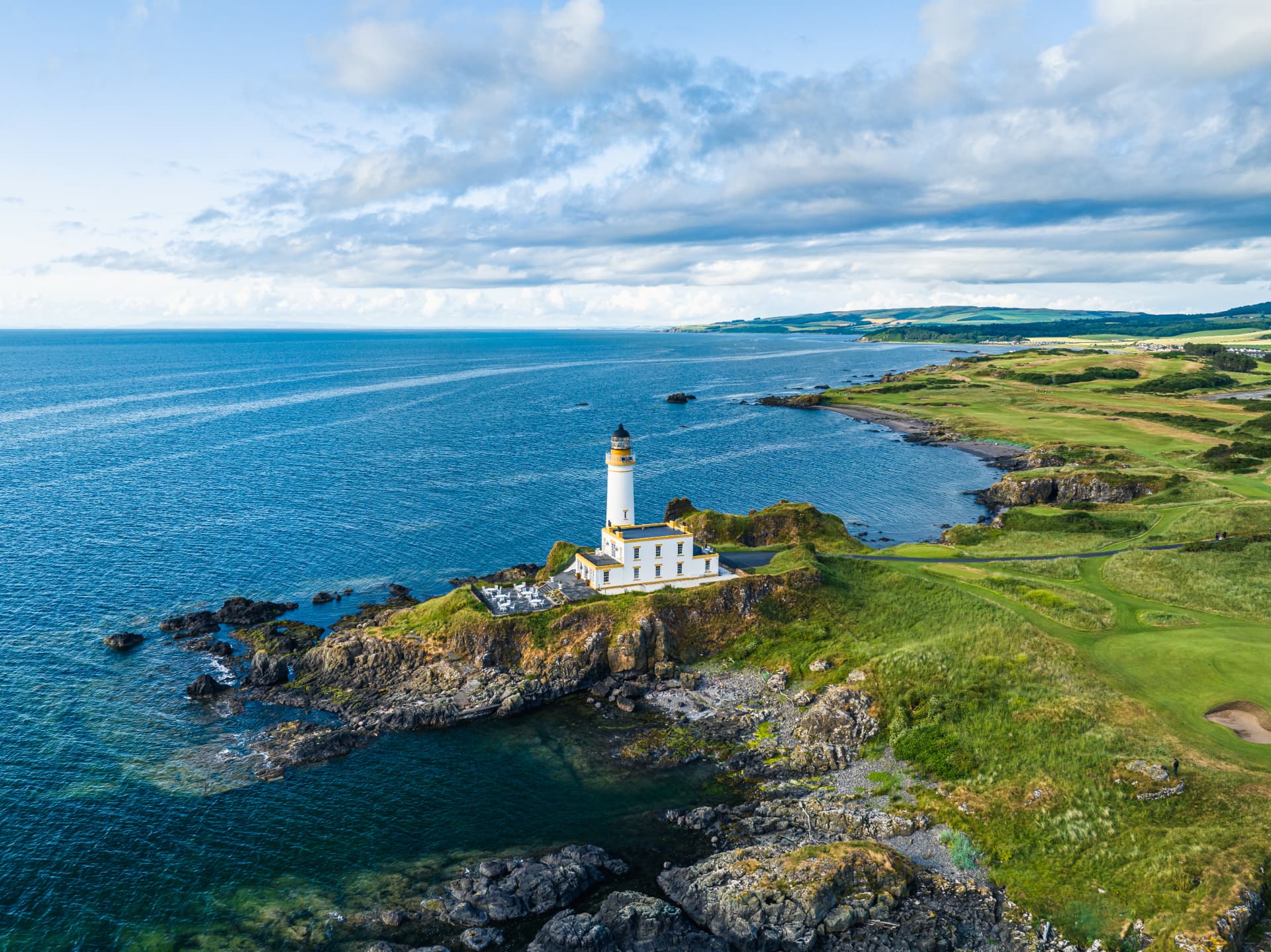 Coastal links at golden hour with lighthouse in the distance
